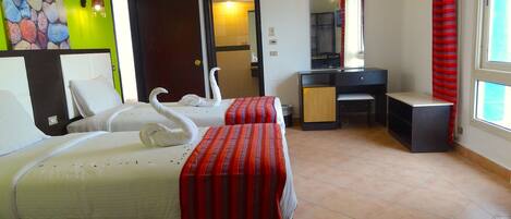 A hotel room with two beds, a desk, a chair, a mirror, and a window with curtains.