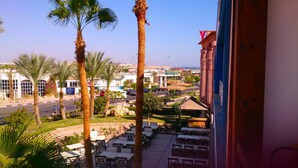 A view of a hotel with outdoor seating, palm trees, and a view of the cityscape. - Naama Blue hotel (Sharm El Sheikh)