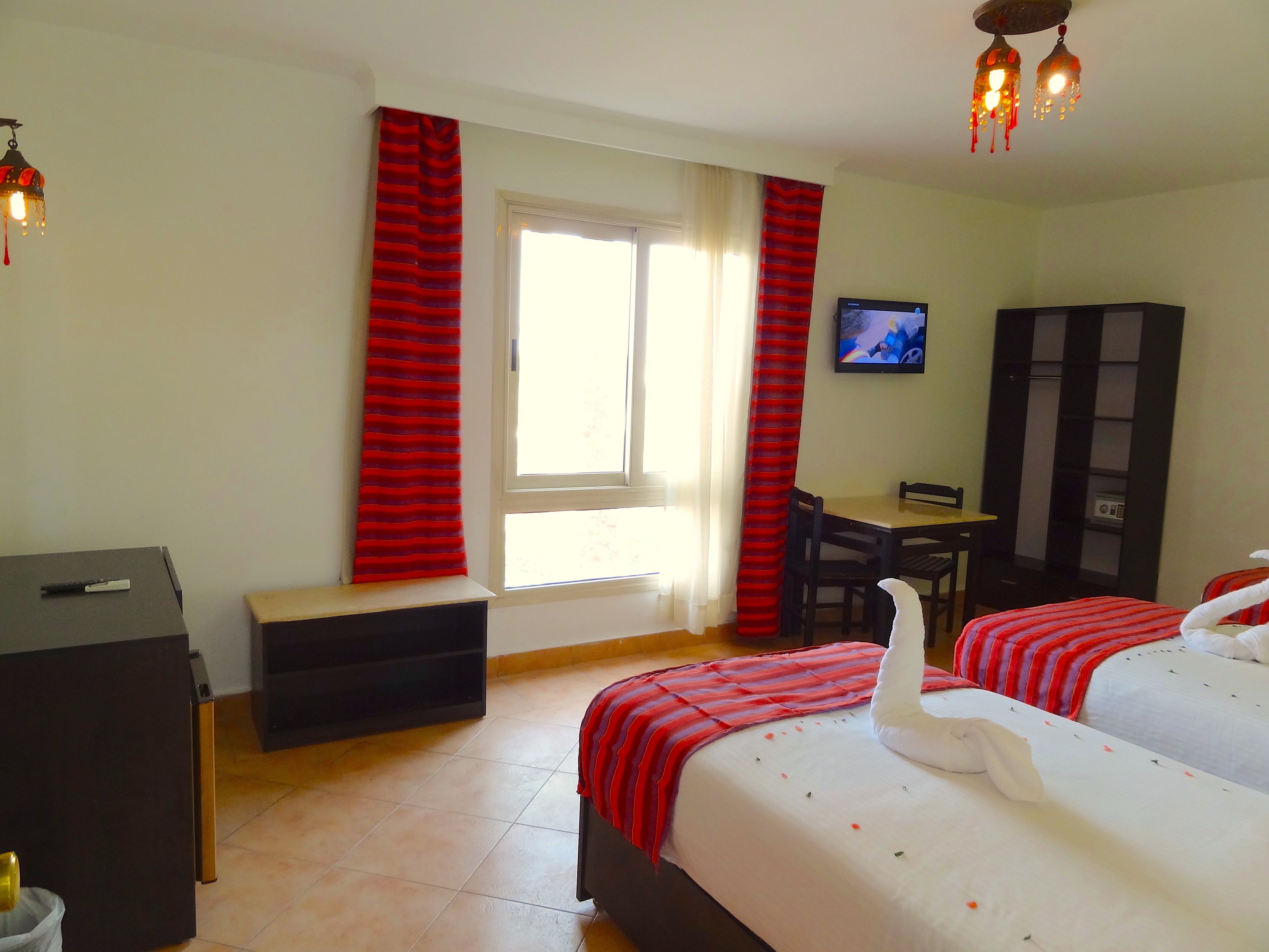 A hotel room with two beds, a desk, a TV, and a wardrobe.