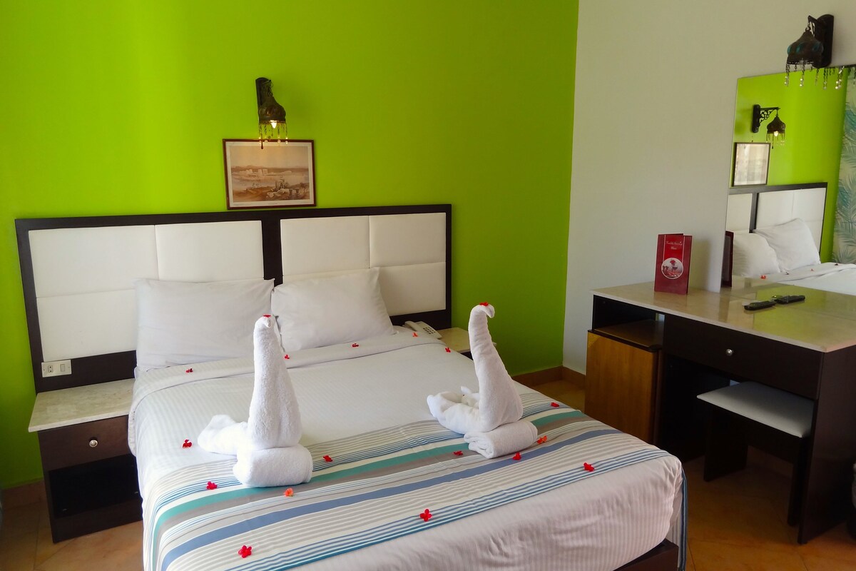 A hotel room with a bed, a desk, and a nightstand.
