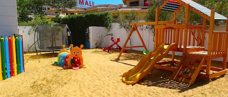 Zona de juegos infantiles con tobogán, estructura de escalada y equipo de juego colorido.