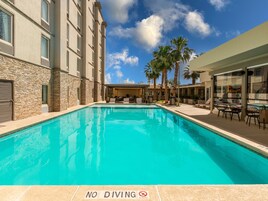 Una piscina al aire libre, sombrillas, sillones reclinables de piscina