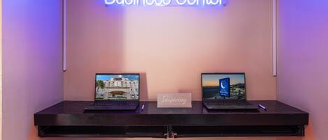 Centro de negocios con dos computadoras portátiles sobre un escritorio, un cartel que dice "Business Center" y un cartel con el texto "Inspiring".