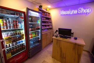 A vending machine area with Coca-Cola and other beverages, a snack shelf, and a reception desk with a computer.