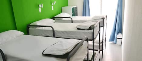Ein Schlafsaalzimmer mit Etagenbetten, einer grünen Wand und einem Fenster mit blauen Vorhängen.