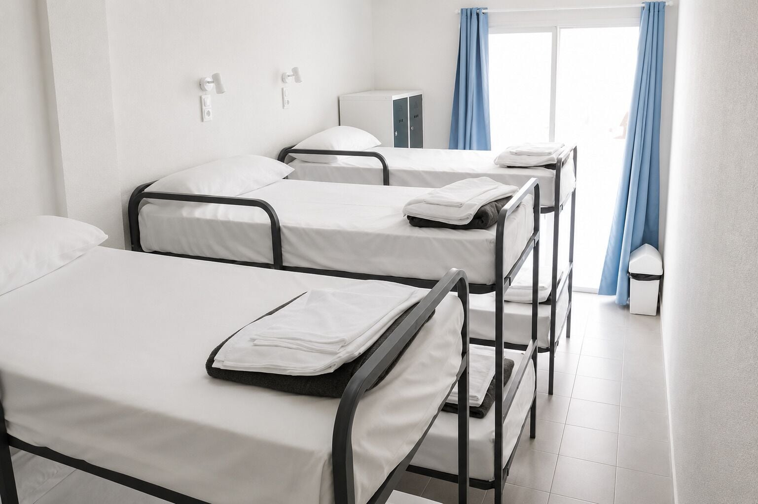 Habitación de hotel con tres camas individuales, un mueble bajo y una ventana con cortinas.