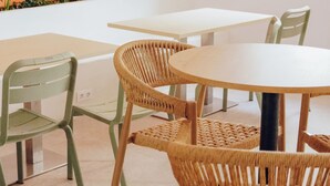 A room with a round table, two wicker chairs, a green chair, and a white table. - El Patio de Chueca - Hostel (Madrid)