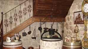 Une cuisine rustique aux murs de pierre, aux poutres apparentes et aux ustensiles de cuisine d’époque.