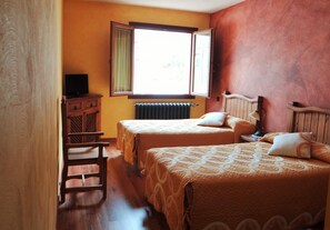 Una habitación con dos camas, un armario de madera y una ventana con cortinas.