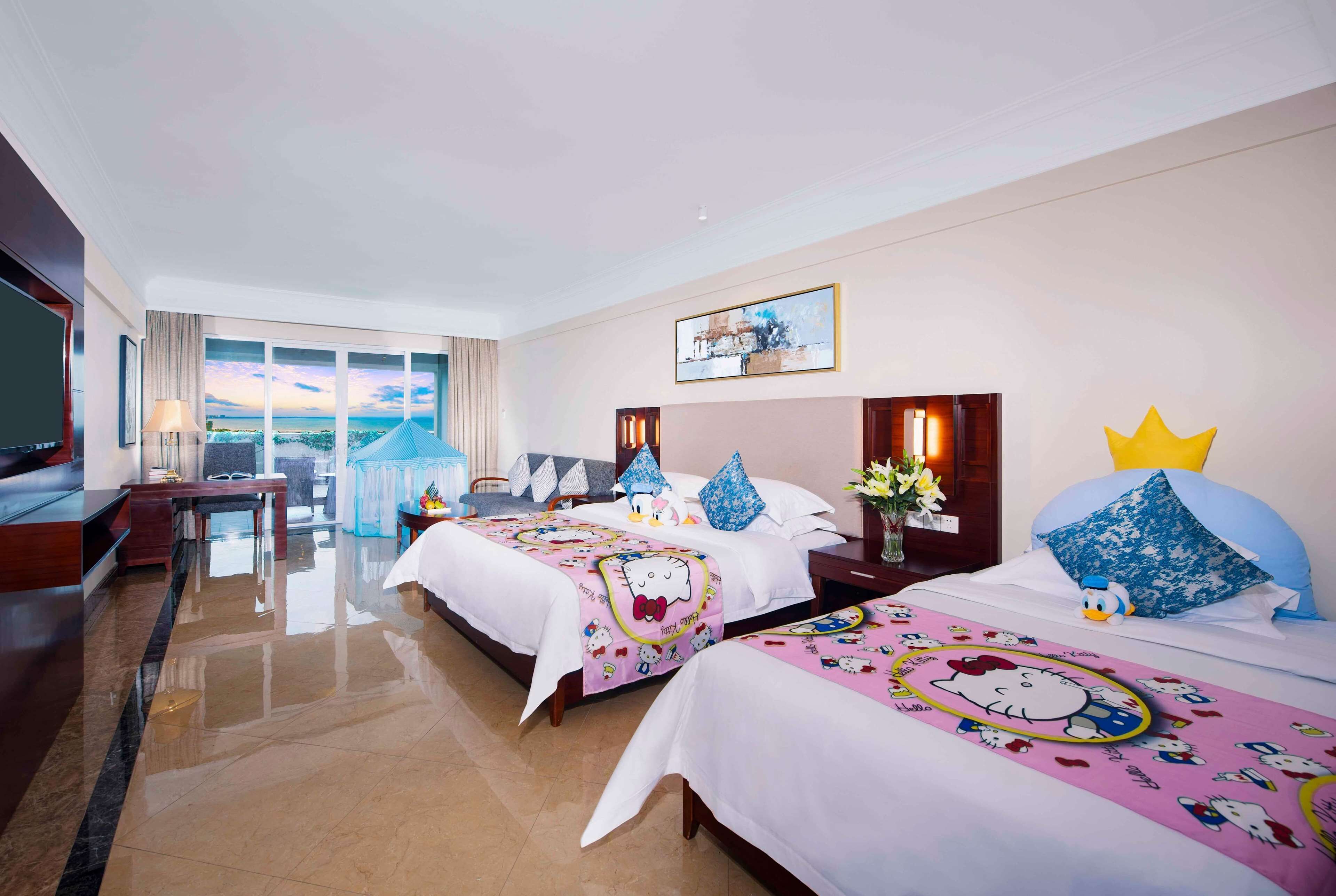 A hotel room with two beds, a TV, a desk, and a view of the city.