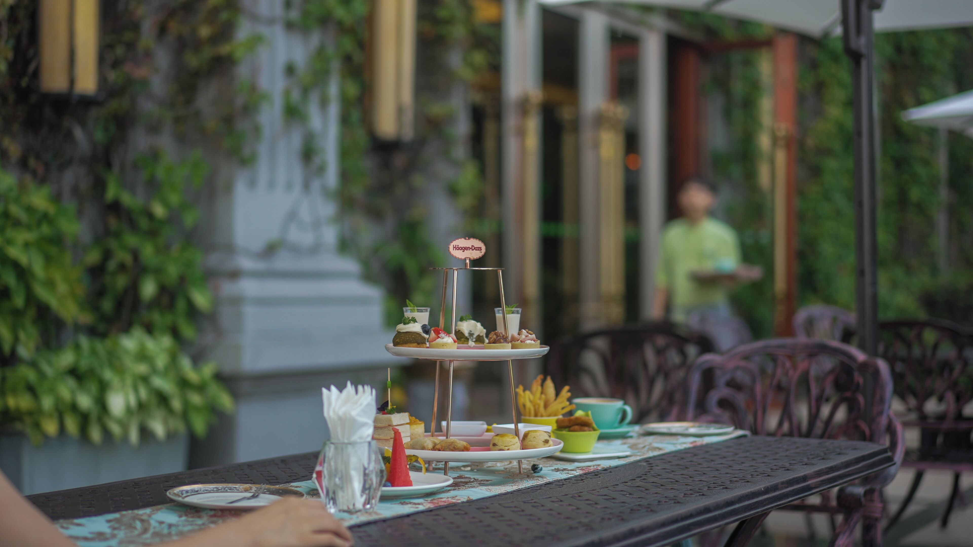 A table set with a variety of desserts and snacks, a sign indicating Häagen-Dazs, and a person in the background.
