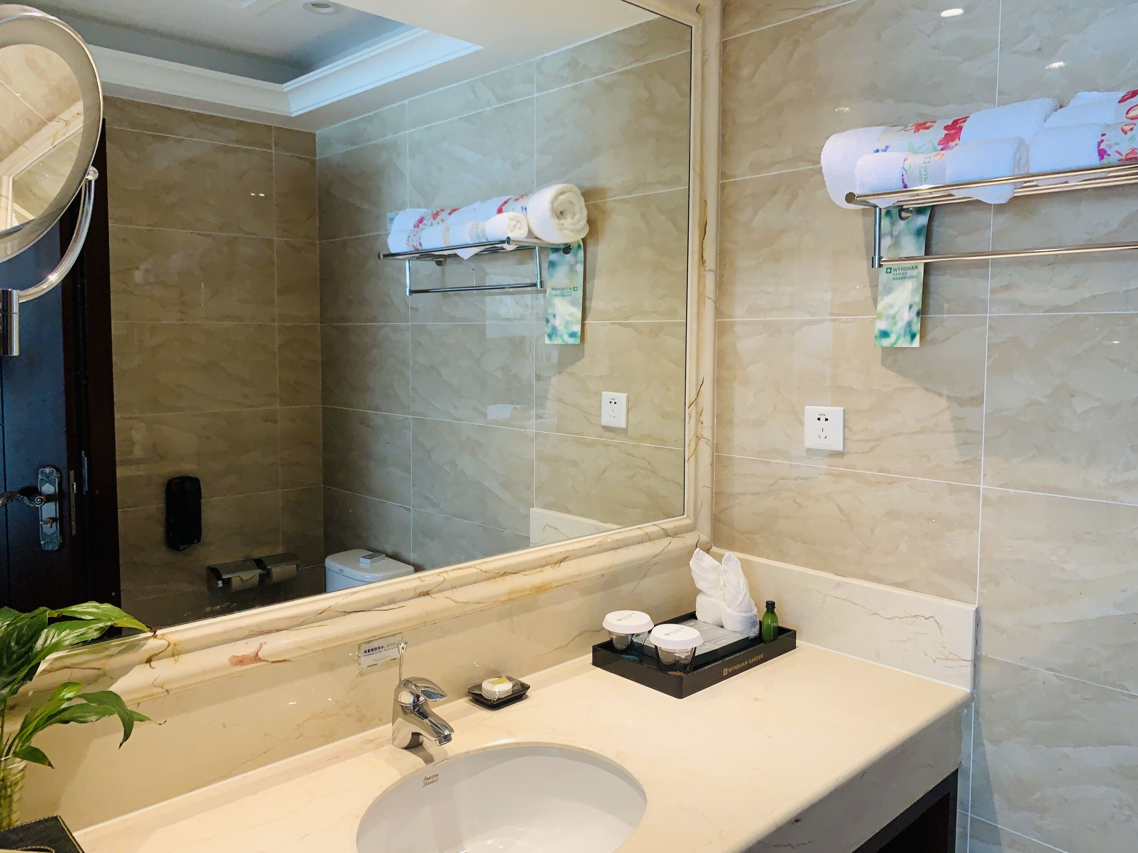 A bathroom with a large mirror, a sink, a towel rack, and a toilet.