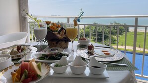 Une table dressée avec différents plats et boissons, offrant une vue panoramique sur l’océan.