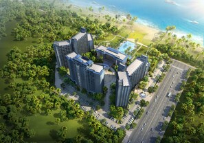 Ein Hochhaus-Hotel mit mehreren Etagen, umgeben von üppiger Vegetation und einem Strand.