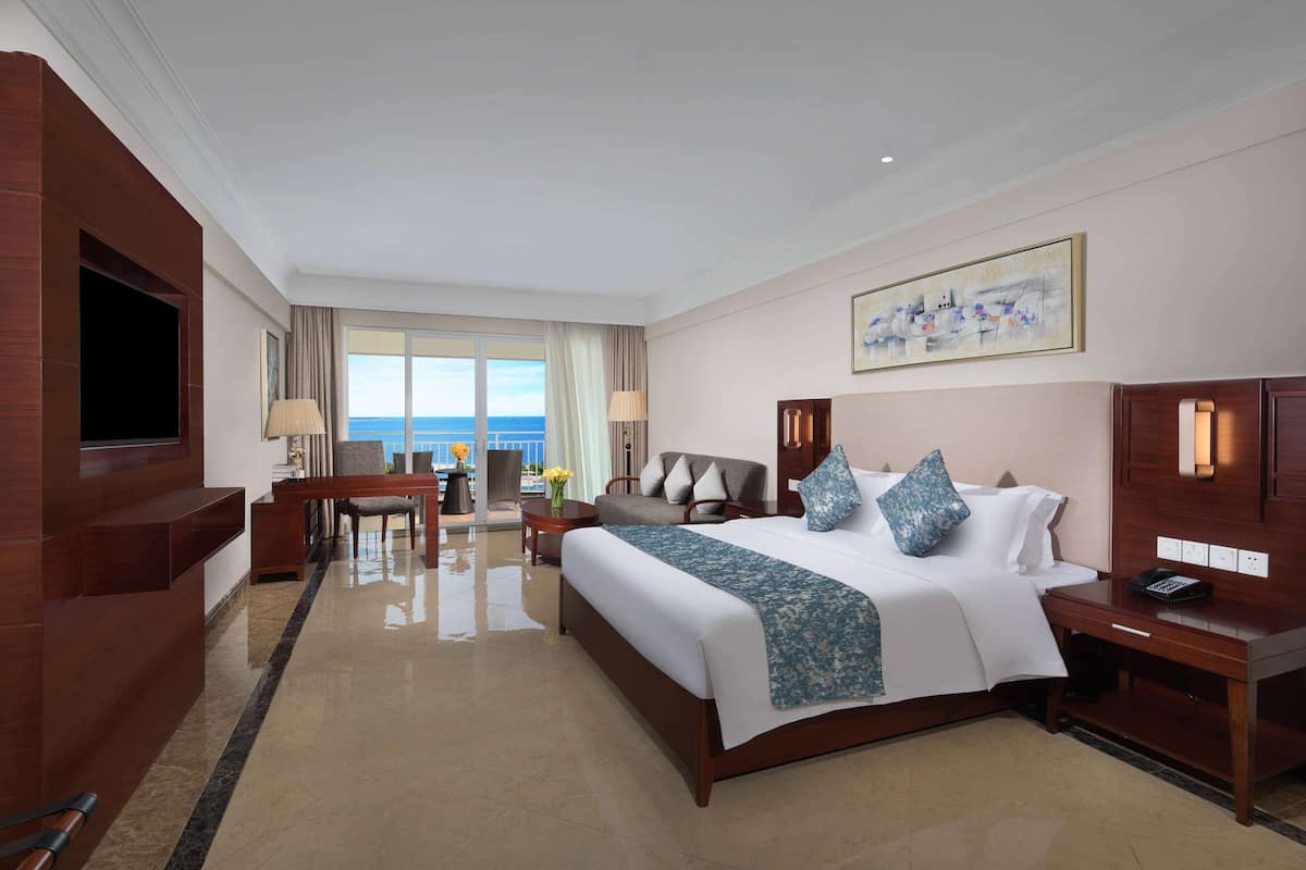 A hotel room with a large bed, a desk, a chair, and a TV.