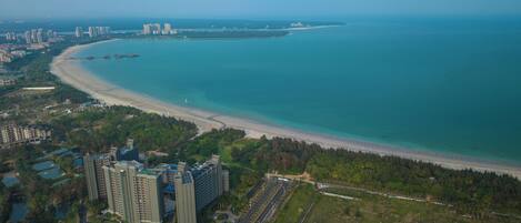 An aerial view of a coastal city with high-rise buildings, a beach, and a marina.