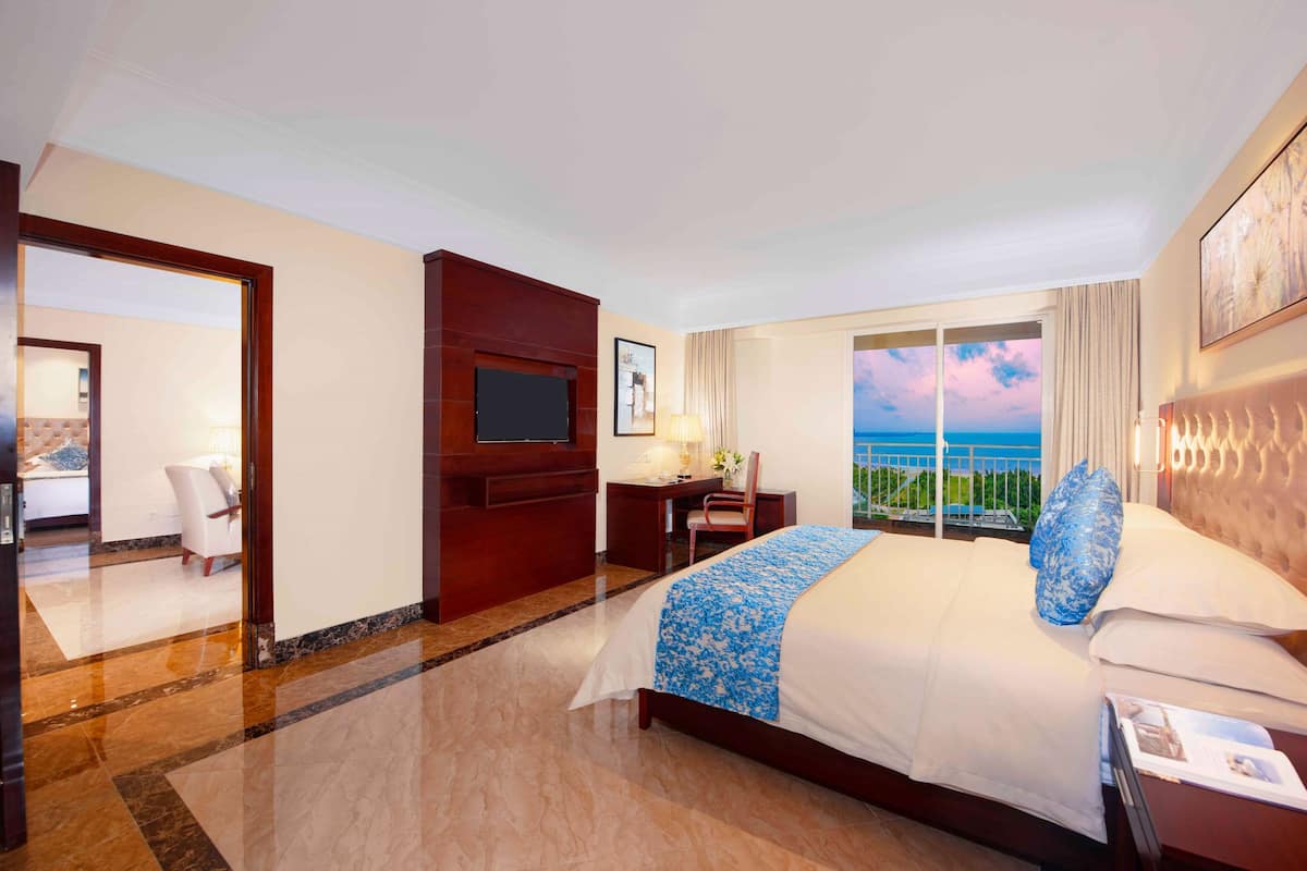 A hotel room with a bed, a desk, a chair, a TV, and a large window with a view.