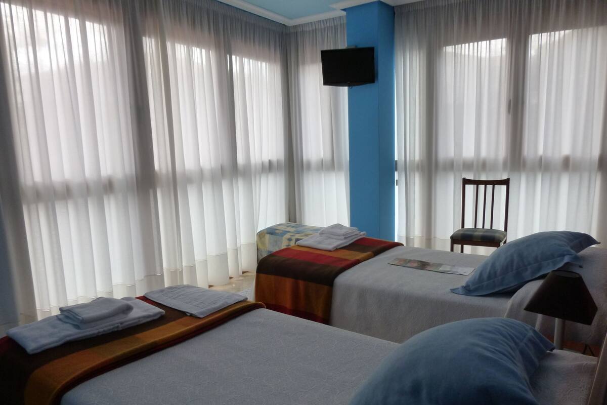 Une chambre d’hôtel avec deux lits, un téléviseur fixé au mur et une chaise.