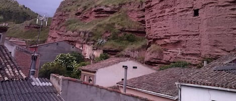 Un edificio tradicional con tejado de tejas, ubicado en una zona montañosa con acantilados rocosos.