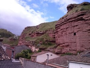 Un edificio tradicional con tejado de tejas, ubicado en una zona montañosa con acantilados rocosos.