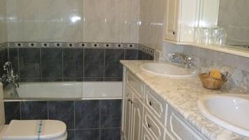 Un baño con una bañera, dos inodoros, un lavabo y un espejo.
