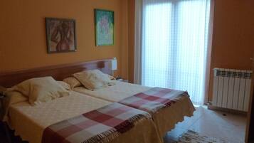 A room with two beds, a radiator, and a window with curtains.