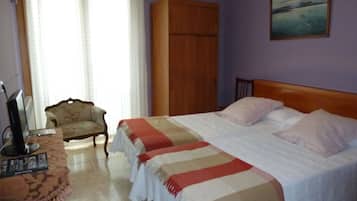 A bedroom with a bed, a wooden wardrobe, a chair, and a painting on the wall.