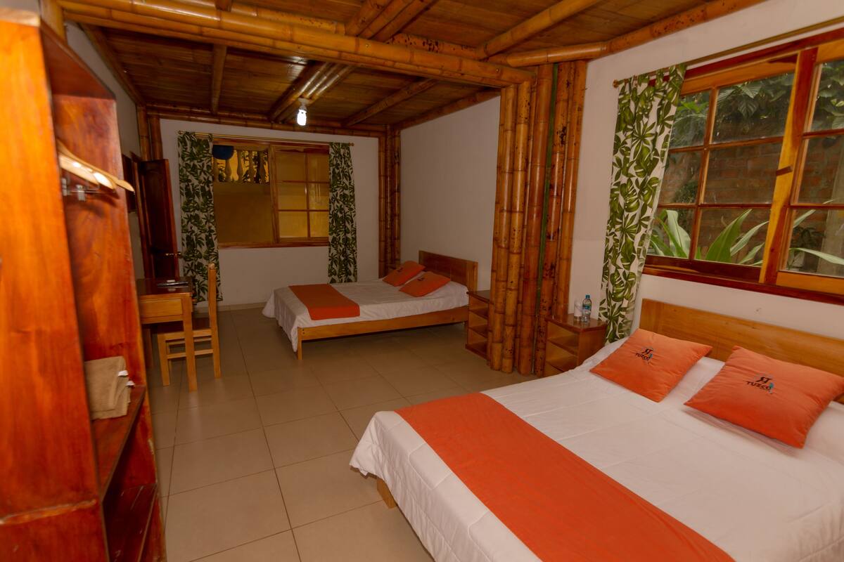 A room with two beds, wooden furniture, and a window with curtains.