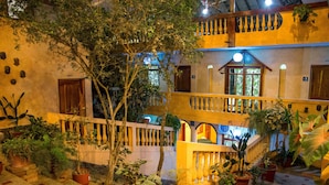 A courtyard with potted plants, a wooden fence, and a balcony with railings. - Tuzco Lodge (Puerto Lopez)