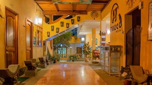 A hotel lobby with a wooden staircase, a reception desk, and potted plants. - Tuzco Lodge (Puerto Lopez)