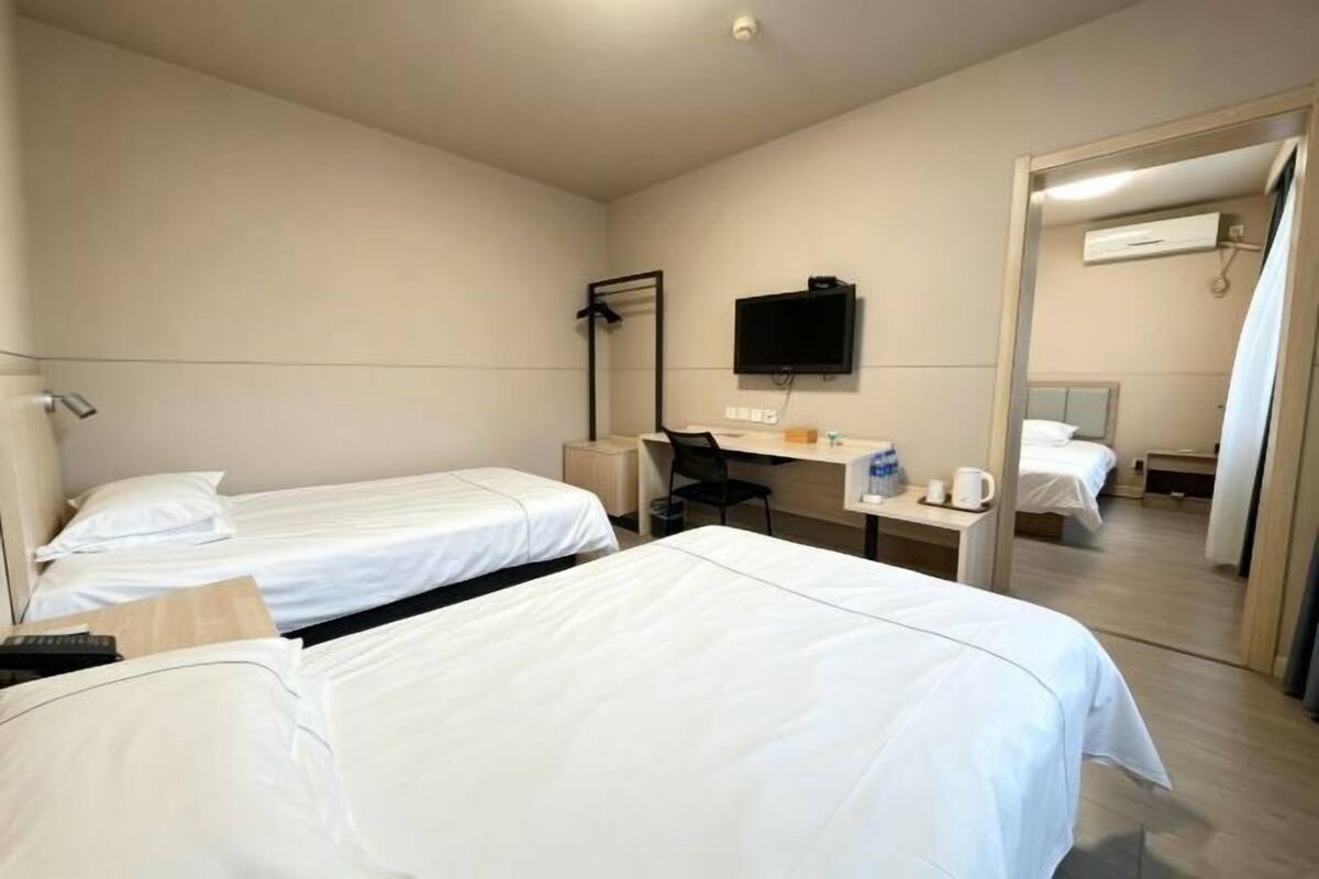 Une chambre d’hôtel avec deux lits, un bureau, une chaise, une télévision et un miroir.