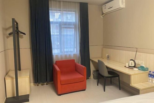 A hotel room with a bed, a desk, a chair, a red armchair, a window with curtains, and a wall-mounted air conditioner. - Jinjiang Inn (Linhai Chonghemen) (TAIZHOU)
