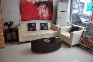 Un vestíbulo moderno con un sofá, sillones, una mesa de centro y un cuadro abstracto grande.