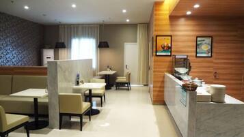 Espaço de refeições de hotel com balcão de receção, áreas de estar e balcão com comodidades.