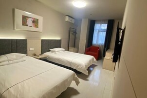 Una habitación de hotel con dos camas, una silla roja, un espejo y un cuadro en la pared.