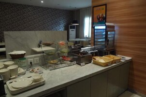 Disposición de bufé con diferentes recipientes de comida y utensilios para servir.
