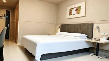 Habitación de hotel con cama, mesita de noche, lámpara y una obra de arte en la pared.