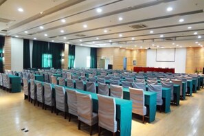 A conference room with rows of tables and chairs, a stage, and a projection screen. - Jinjiang Inn (Linhai Chonghemen) (TAIZHOU)