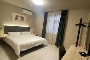 A hotel room with a bed, bedside tables, a desk, a chair, a coat rack, and a window with curtains. - Jinjiang Inn (Linhai Chonghemen) (TAIZHOU)