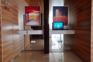A hallway with wooden paneling, two digital screens displaying abstract art, and a marble reception desk. - Jinjiang Inn (Linhai Chonghemen) (TAIZHOU)