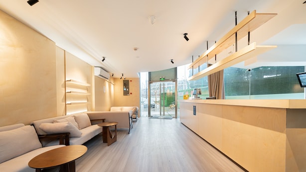 A modern hotel lobby with a reception desk, seating area, and large windows. - Dunbar Inn Zhenbein Road (Shanghai)