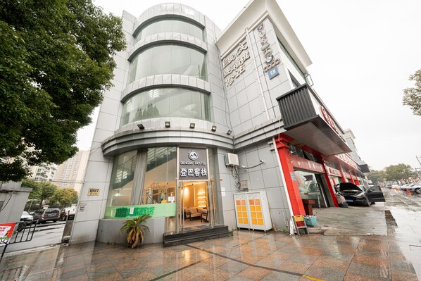A modern building with a curved facade, a visible entrance, and a sign indicating a hostel. - Dunbar Inn Zhenbein Road (Shanghai)