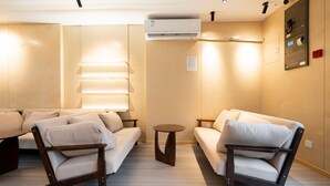 A modern living room with two sofas, a coffee table, and a wall-mounted air conditioner. - Dunbar Inn Zhenbein Road (Shanghai)