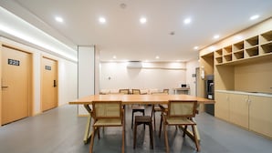 A conference room with a long table and chairs, wooden doors, and a kitchenette area. - Dunbar Inn Zhenbein Road (Shanghai)