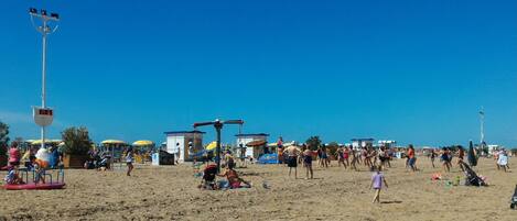 A beach with people sunbathing, umbrellas, and beach equipment.