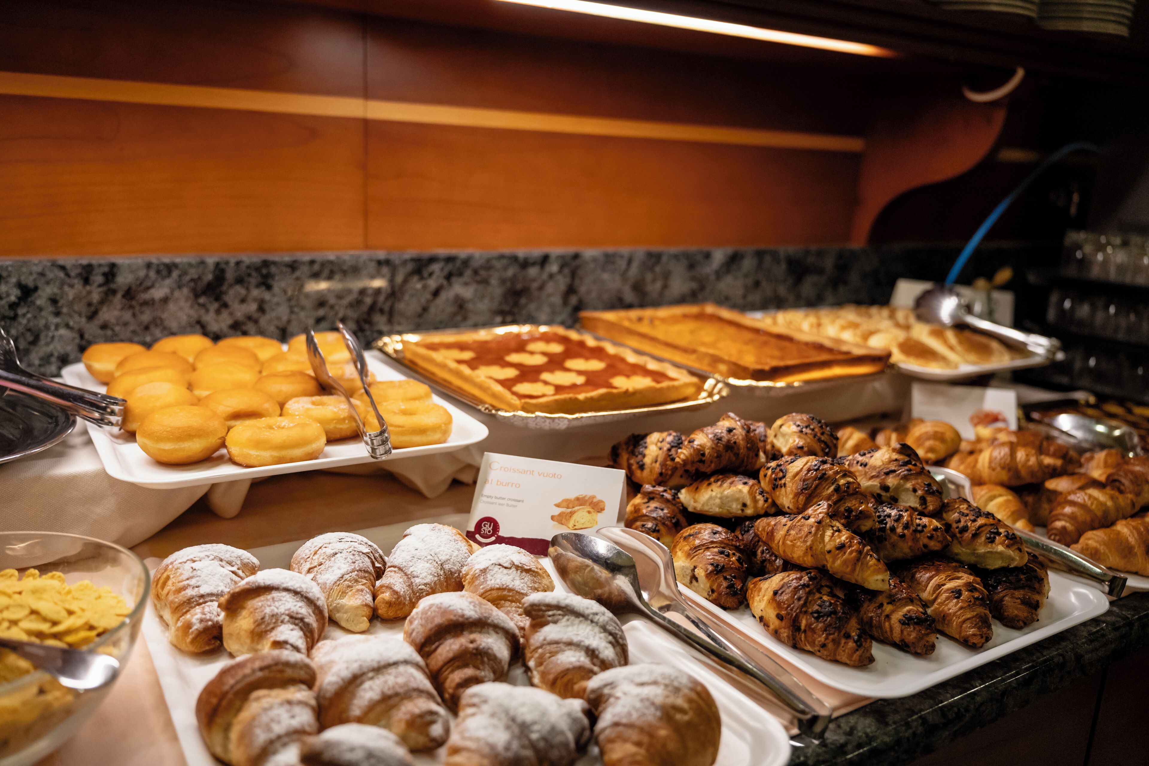 A buffet with various pastries including croissants, danishes, and other baked goods.