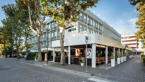 A building with a sign reading "Apartments Pineda" and a covered outdoor area with seating.