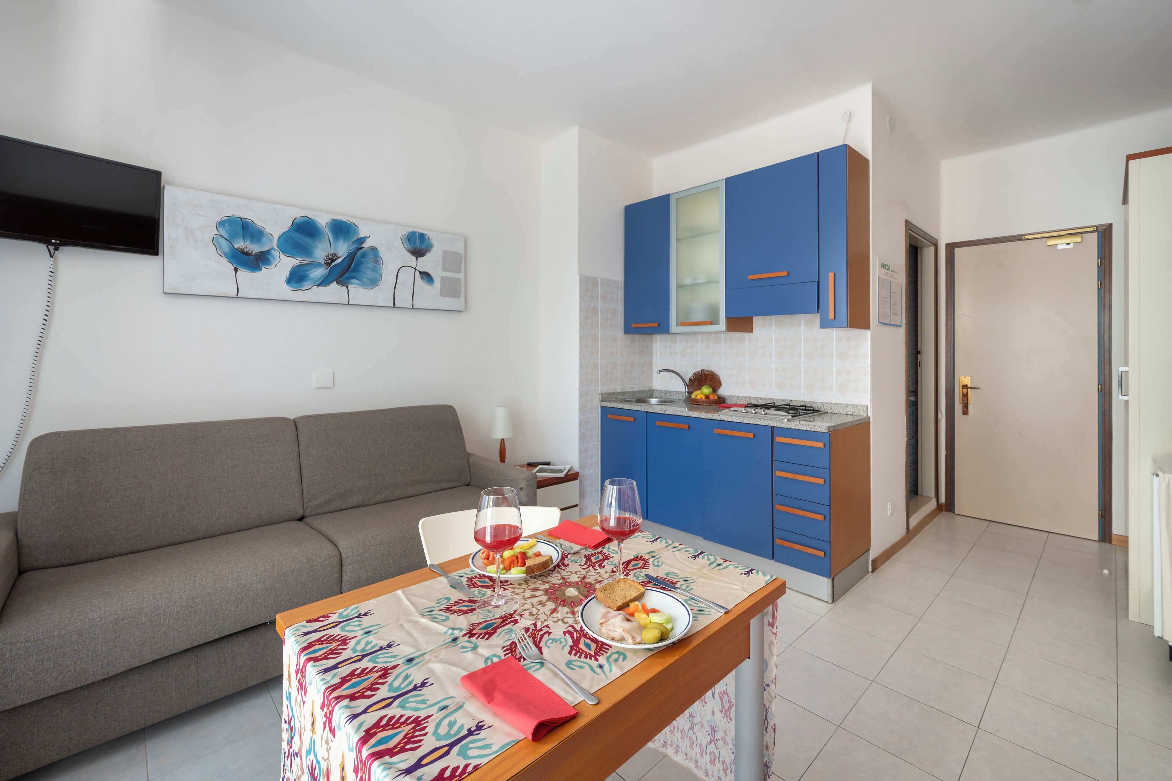 Een ruimtelijk ingerichte leefruimte met een bank, eettafel en kitchenette.