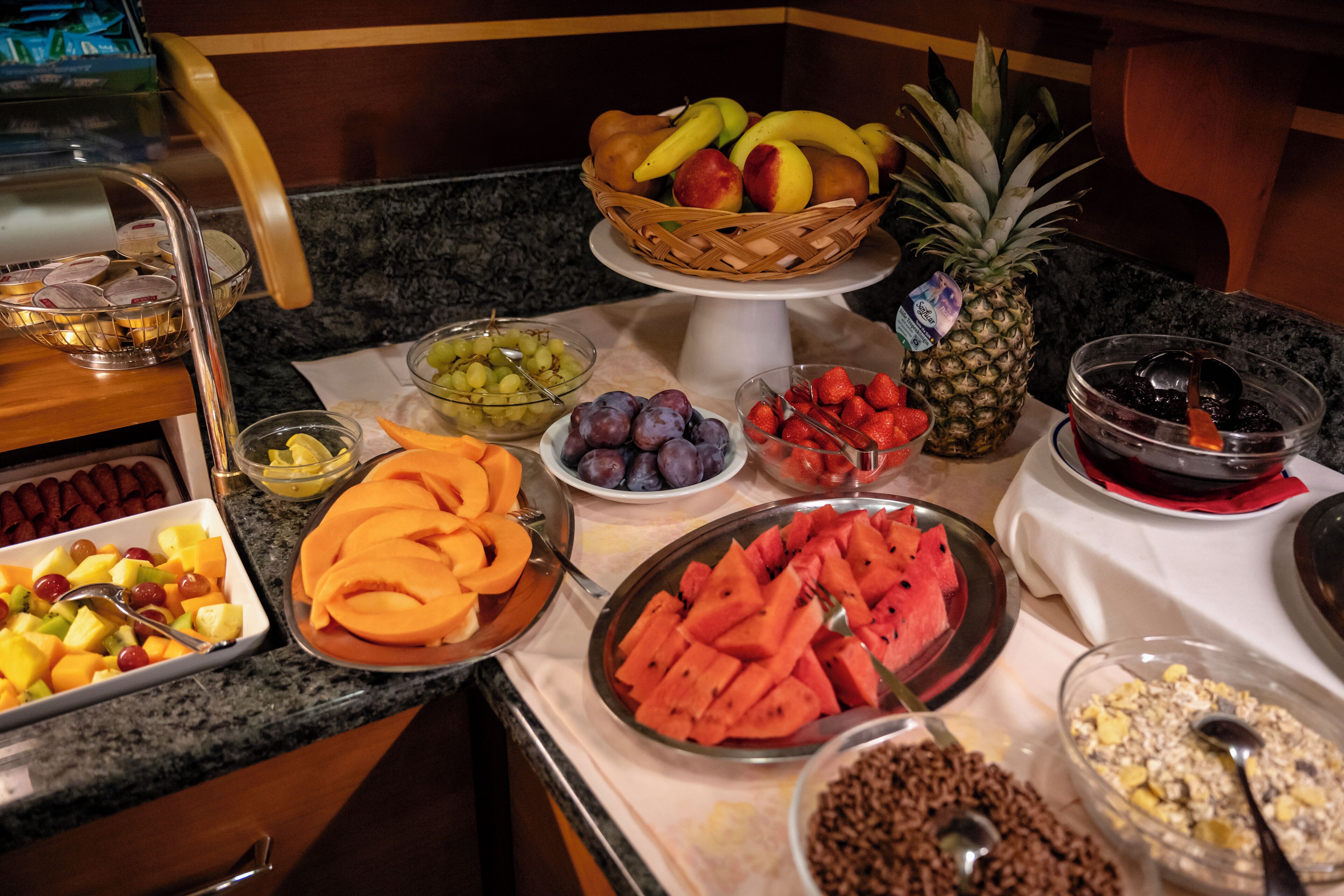 Buffet com diversas frutas e legumes, incluindo melancia, abacaxi e uvas.