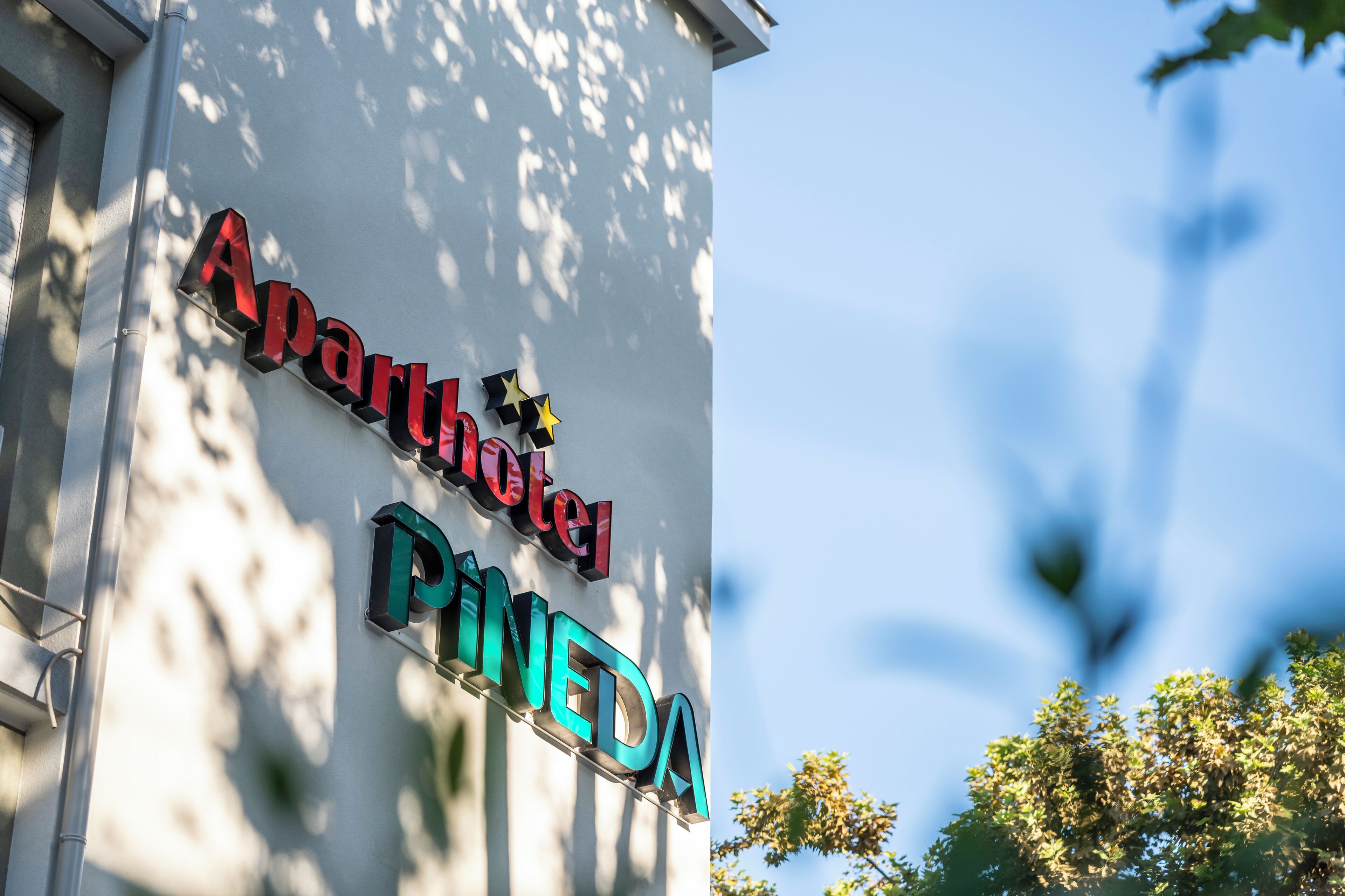 A hotel sign with the name "Aparthotel Pineda" in large, colorful letters.